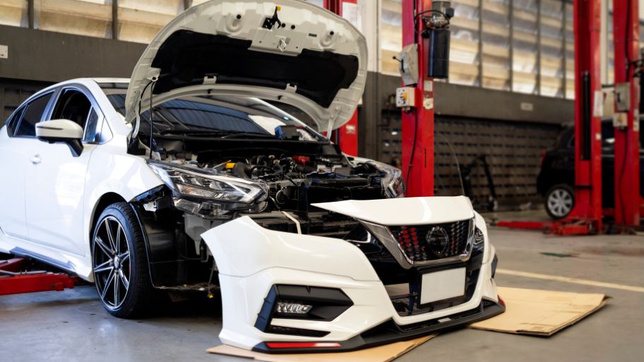 Scotty’s Body Shop performing front-end repair on a white vehicle at their auto body shop in West Des Moines, IA
